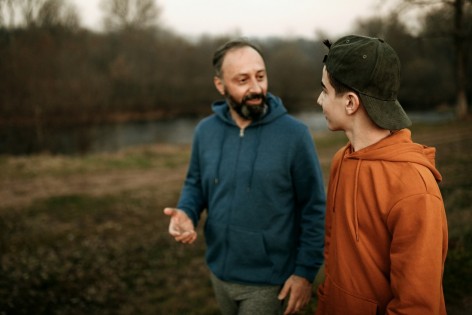 Vater unterhält sich beim Spaziergang am See mit seinem ca 14-jährigen Sohn