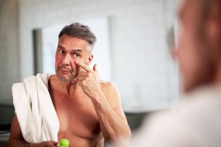Etwa 50-jähriger Mann trägt Creme im Gesicht auf.