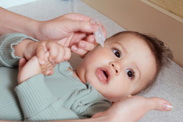 Mutter tröpfelt ihrem Baby Kochsalzlösung in die Nase