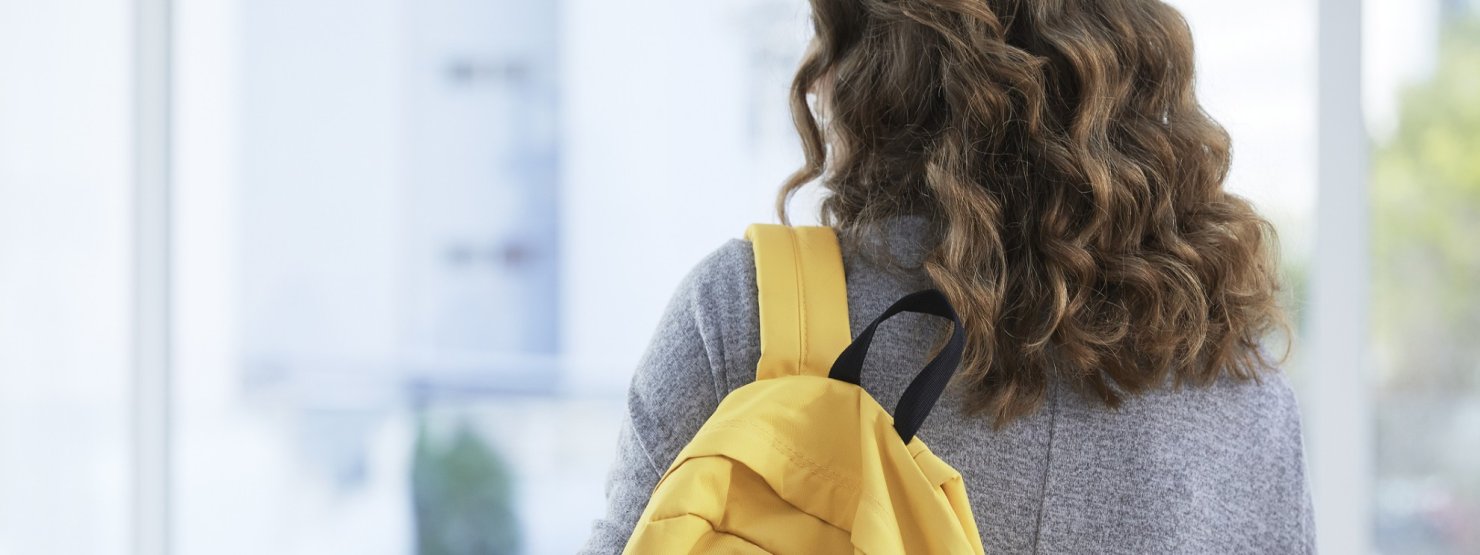 Ein ca. 14-jähriger Junge sitzt vor der schule auf einer Stufe und scha ut traurig auf sein Smartphone