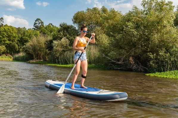 Eine junge Frau beim Stand-up-Paddling auf einem kleinen Fluss