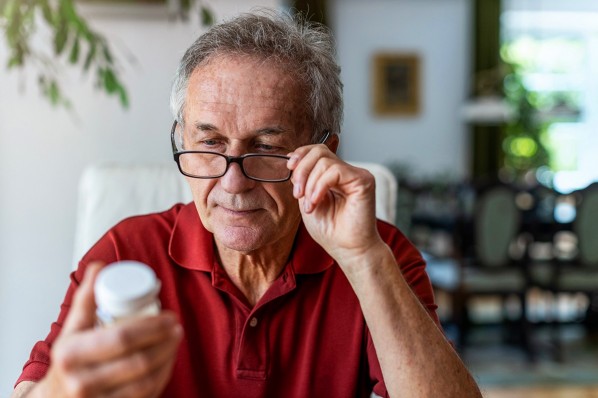 Ein etwa 60-jähriger Mann liest die Angaben auf seinem Medikament.