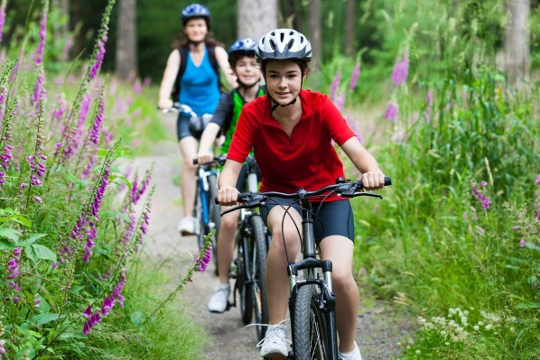 Zwei Kinder und eine Mutter fahren gemeinsam in der Natur Fahrrad.