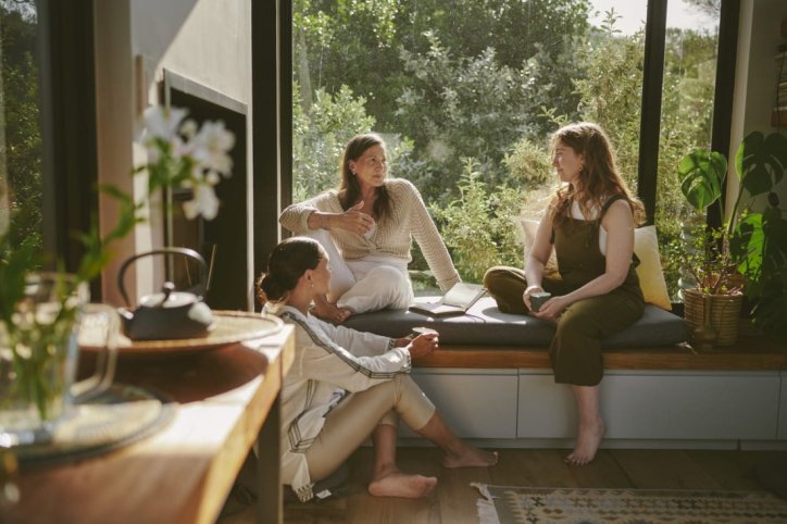 Drei Frauen sitzen auf einem Fensterbrett und unterhalten sich