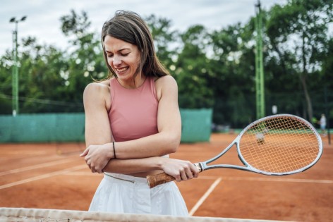 Eine Frau hat sich beim Tennisspielen eine Sportverletzung zugezogen