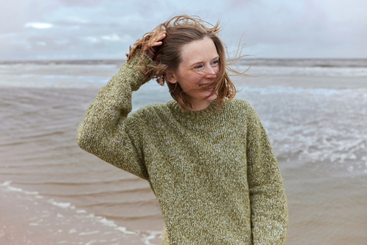 Frau genießt am Stand eine Auszeit für ihre Gesundheit. - AOK Sachsen-Anhalt fördert Gesundheitsreisen.