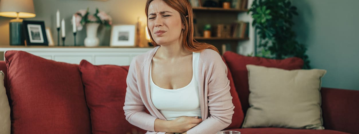 Eine Frau mit Norovirus-Infektion hält sich den Bauch vor Schmerzen