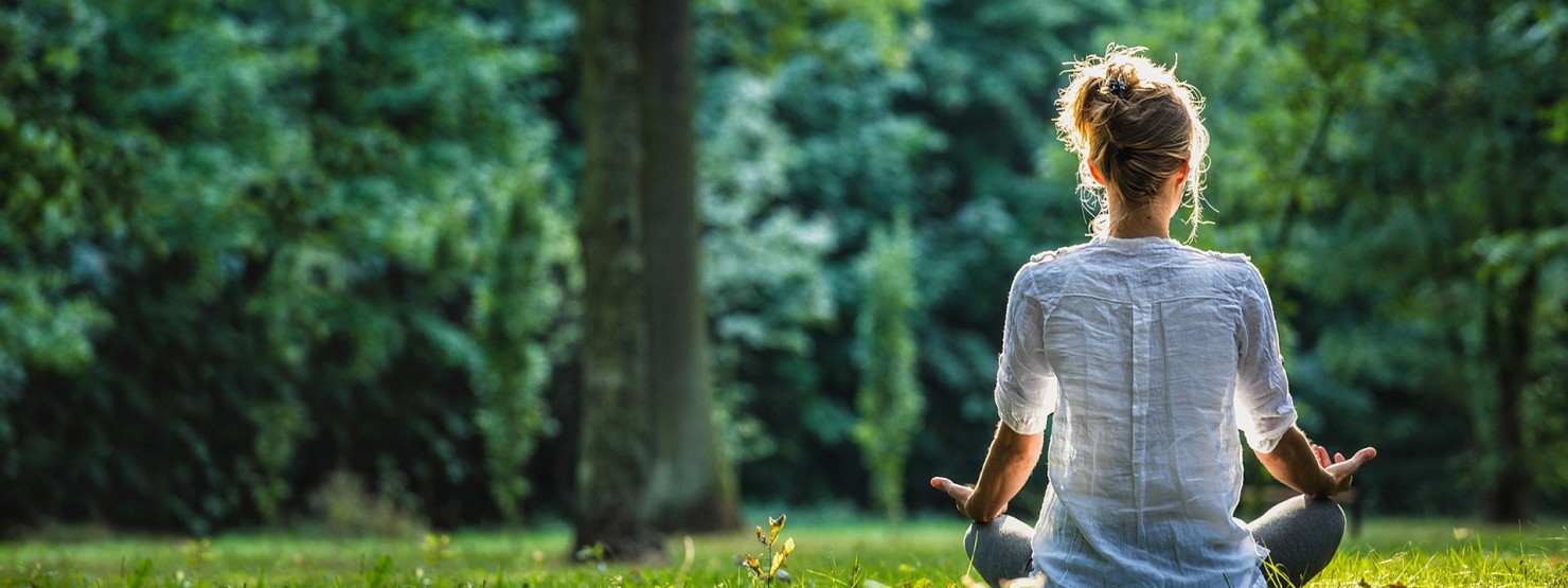 Eine Frau sitzt im Wald auf einer Wiese