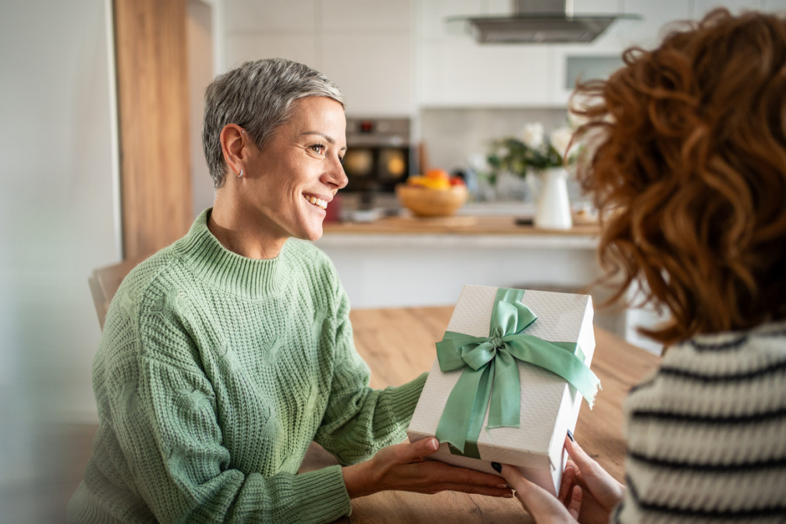 Frau, die ihrer Freundin zu Hause ein Geschenk macht