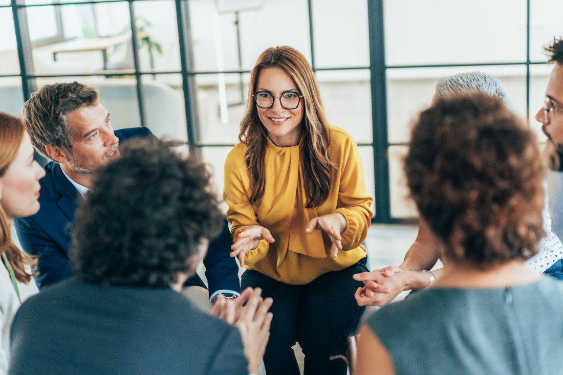 Business people having a meeting. Group of Business persons sitting in circle in board room, talking and gesturing while discussing ideas. Sharing ideas and supporting each other. Positive team motivation