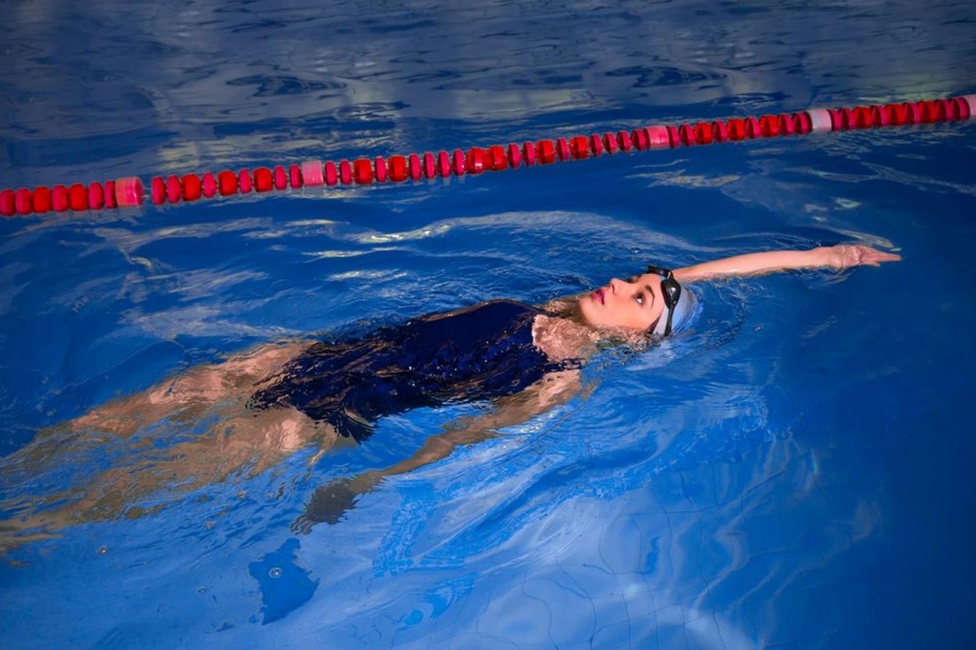 Schwimmerin beim Rückenschwimmen im Schwimmbad