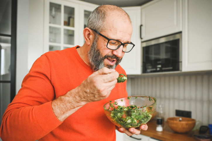 Ein Mann mit Morbus Crohn isst einen gesunden grünen Salat.