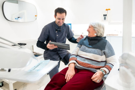 Junger Zahnarzt behandelt Seniorin in seniorenfreundlicher Praxis