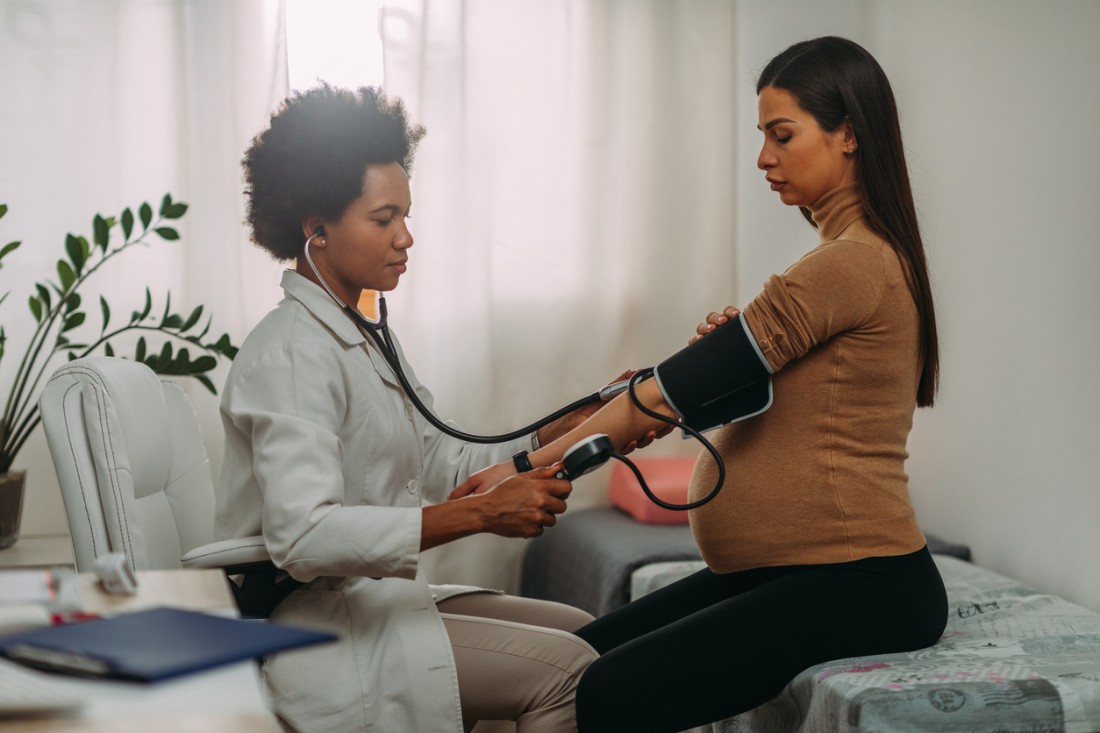 Ärztin mißt bei einer Schwangeren den Blutdruck