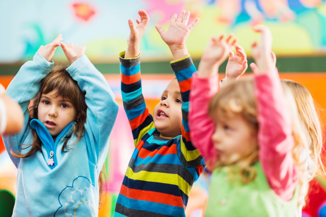 3 Kita Kinder tanzen und heben die Arme in die Luft.