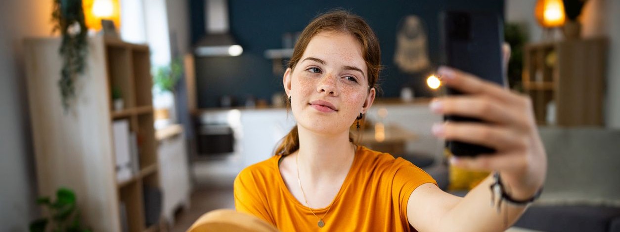 Ein etwa 14-jähriges Mädchen macht ein Selfie mit ihrem Handy.