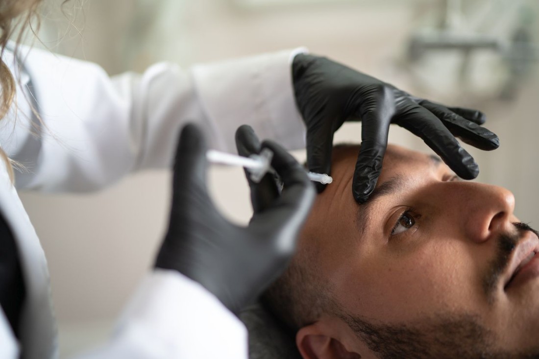 Ein Mann lässt sich in seine Stirn Botox spritzen.