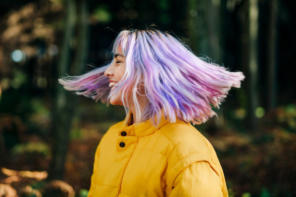 Junge Frau im Wald mit wehenden lila haaren