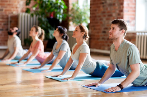 Eine Gruppe nimmt an einem Präventionskurs teil. Sie machen Yoga auf der Matte.