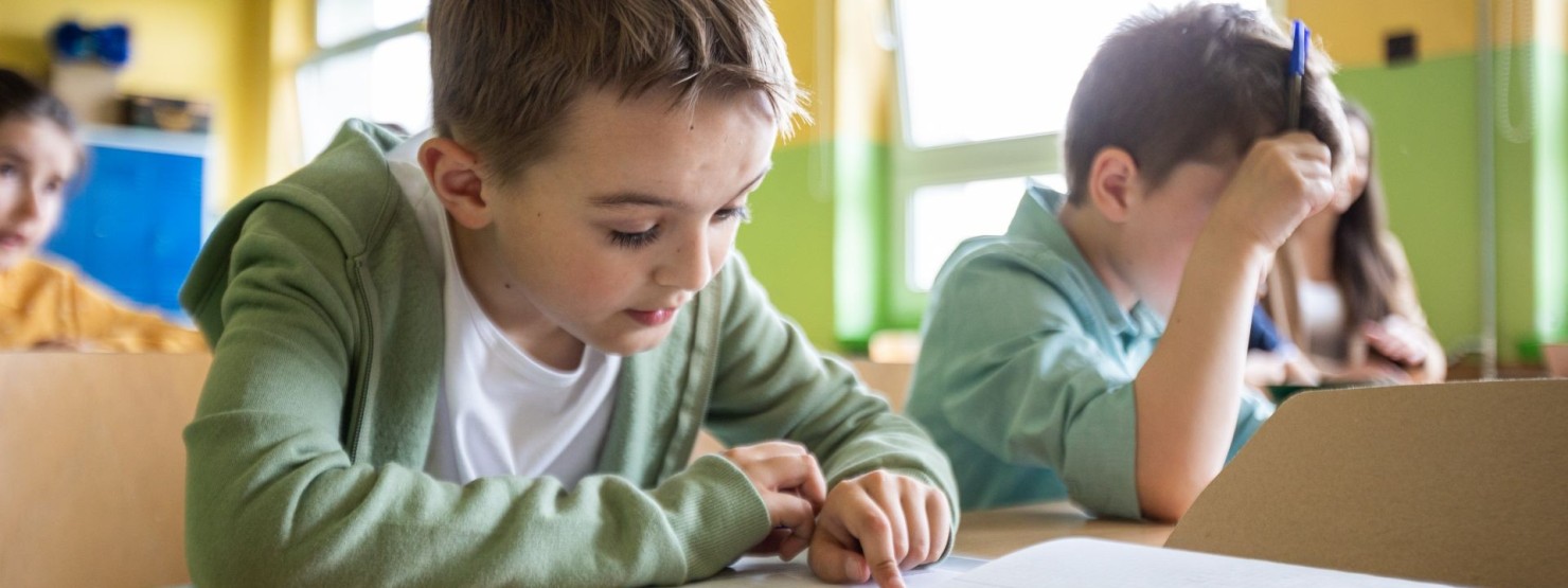 Ein etwa 9 jähriger Junge sitzt bei eine Logopädin und macht mit ihr gemeinsam Sprechübungen.