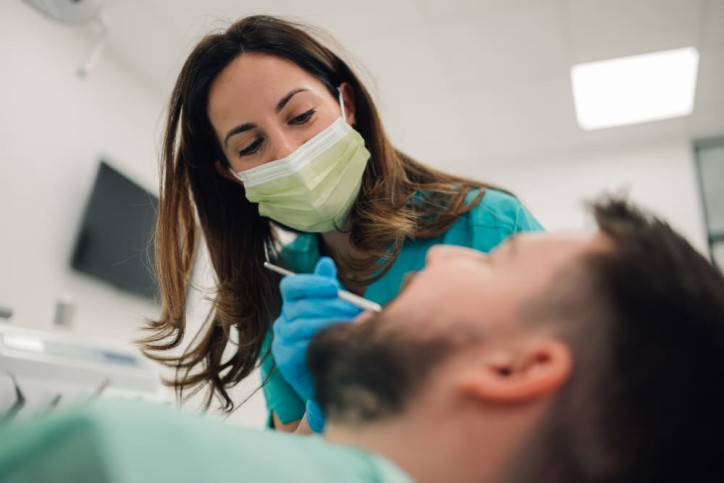 Eine Zahnärztin untersucht einen Patienten, der unter Zähneknirschen leidet