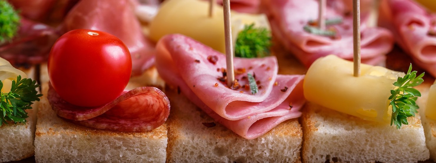 Kleine Schnittchen mit Wurst, Käse und Tomate garniert mit Petersilie