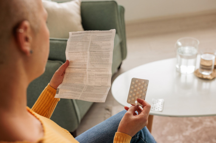 Eine Frau liest sich einen Beipackzettel eines Medikaments durch.