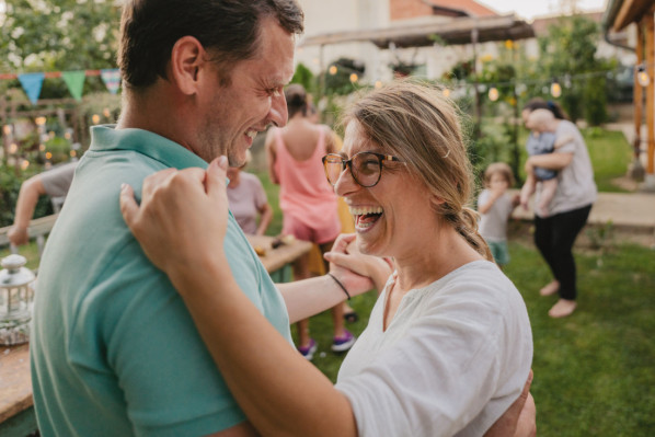 Paar, etwa Mitte 40, tanzt lachend im Garten miteinander. - AOK Sachsen-Anhalt begleitet mit starken Leistungen.